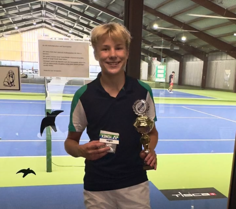 Junge mit Pokal in Tennishalle