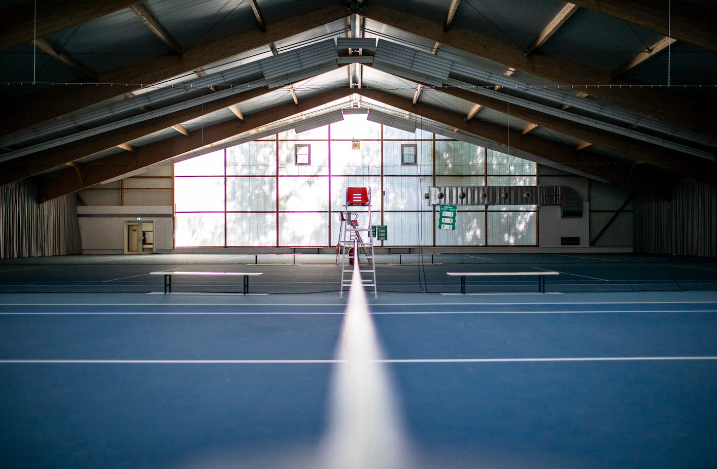 Leerer Indoor-Tennisplatz mit Netz und Schiedsrichterstuhl