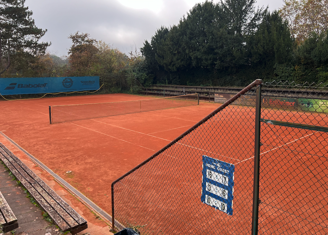 Leerer Sand-Tennisplatz mit Netz und Zaun