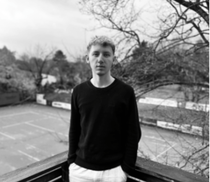 Junger Mann auf Balkon vor Tennisplätzen