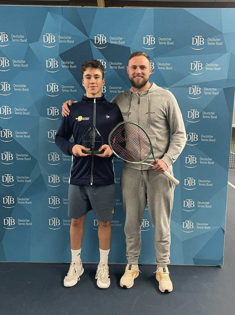Zwei Tennisspieler mit Pokal vor DTB-Wand