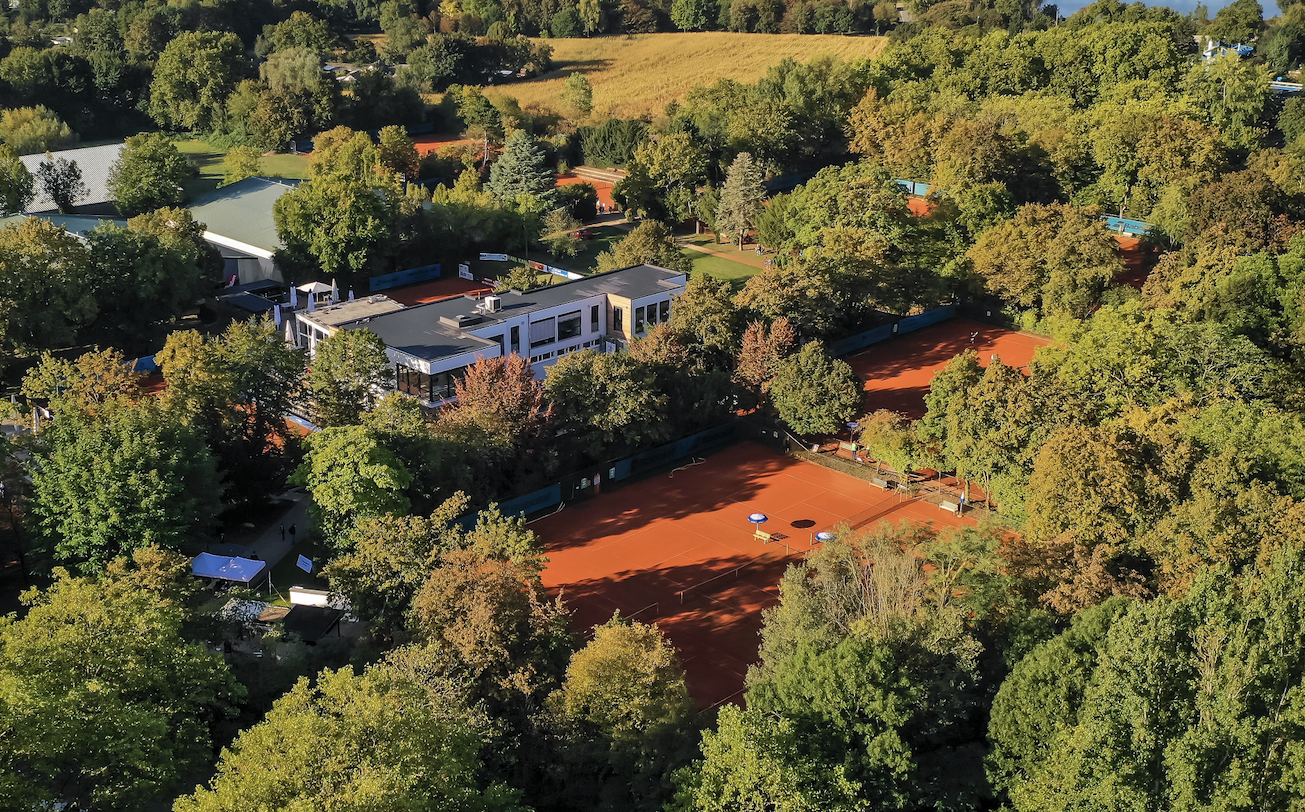 Luftaufnahme von Tennisanlage mit Sandplätzen im Grünen