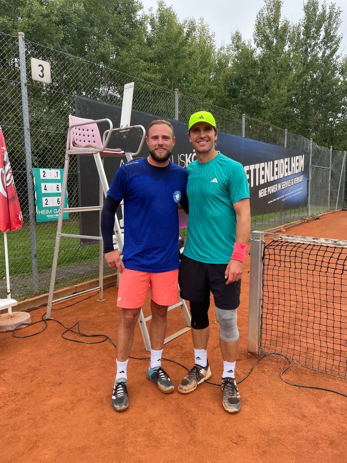 Zwei Tennisspieler auf Sandplatz neben Netz