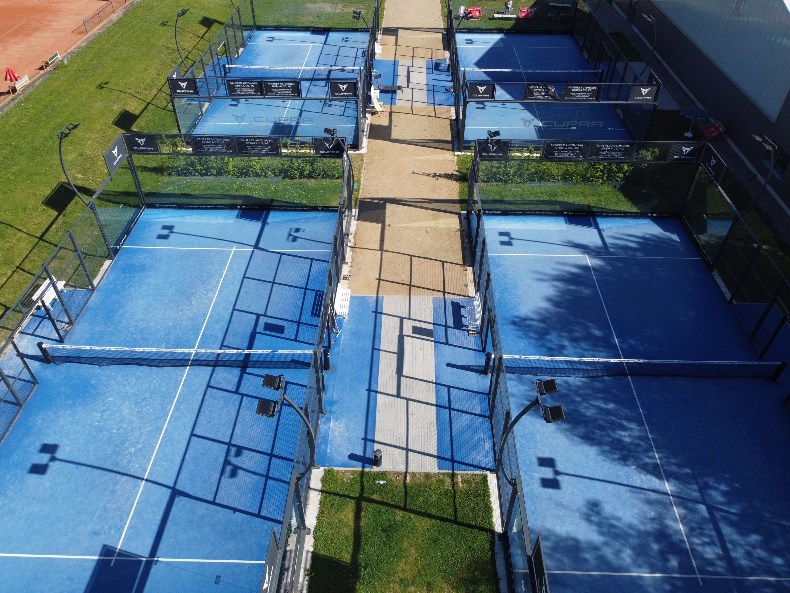 Luftaufnahme mehrerer blauer Padelplätze im Freien