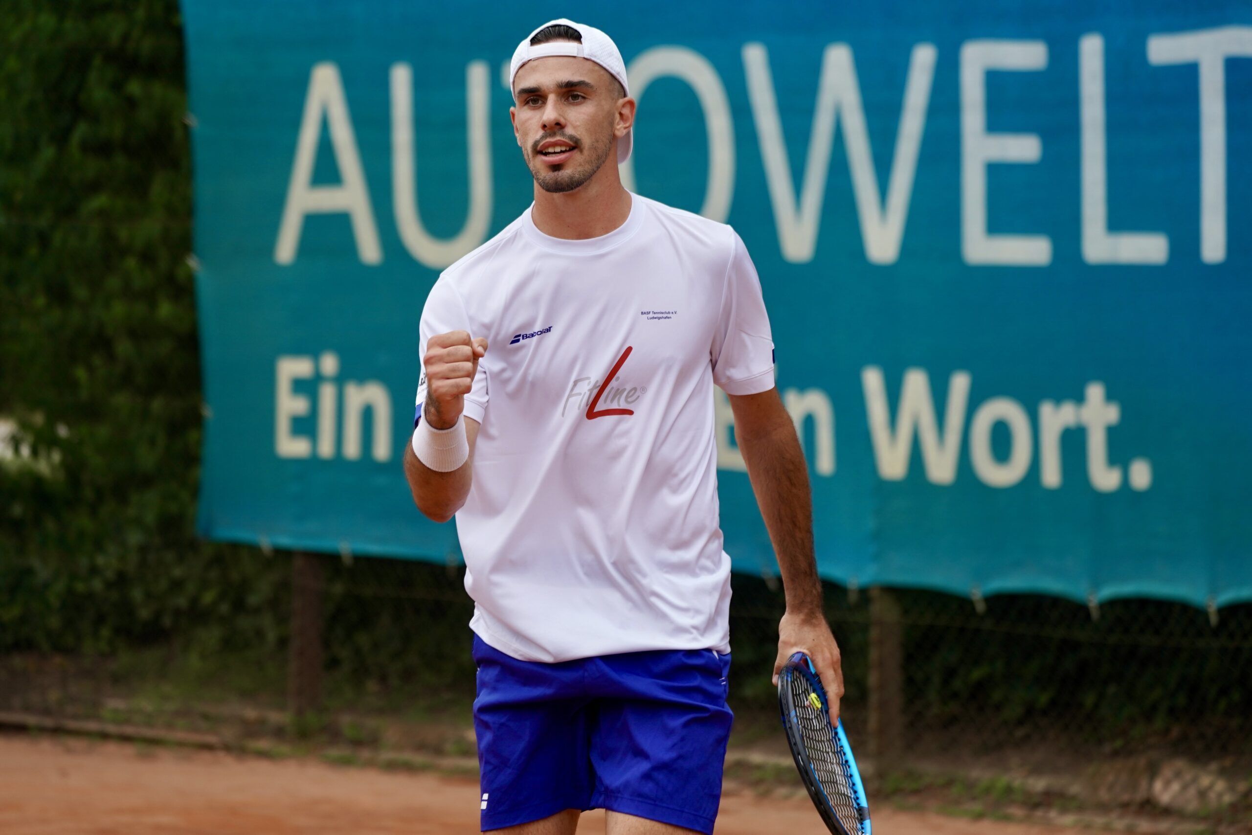 Tennisspieler jubelt auf Sandplatz mit Schläger