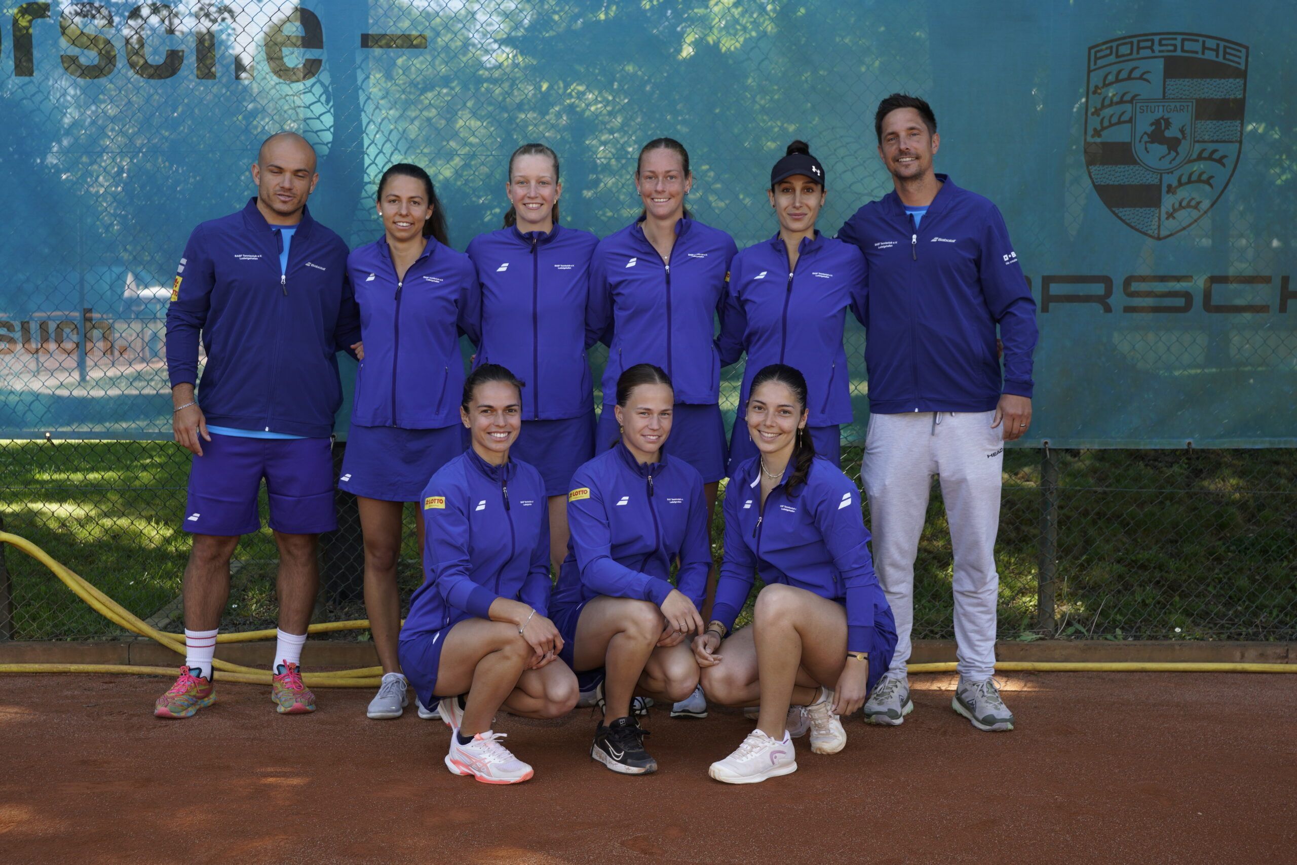 Tennisteam in lila Trainingsanzügen auf Sandplatz