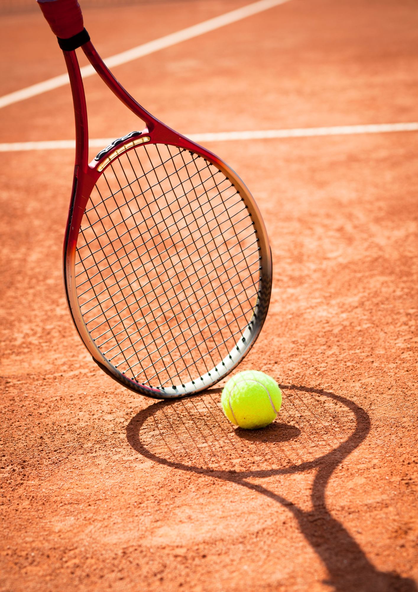 Tennisschläger und Ball auf Sandplatz