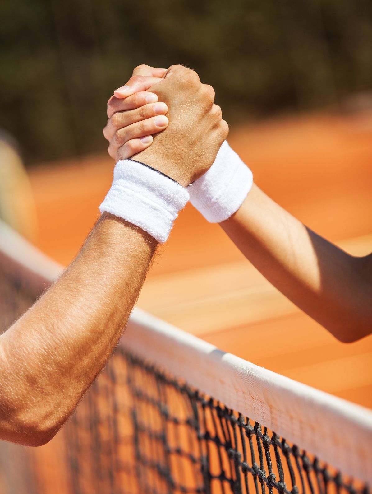 Tennisspieler geben sich Hand am Netz