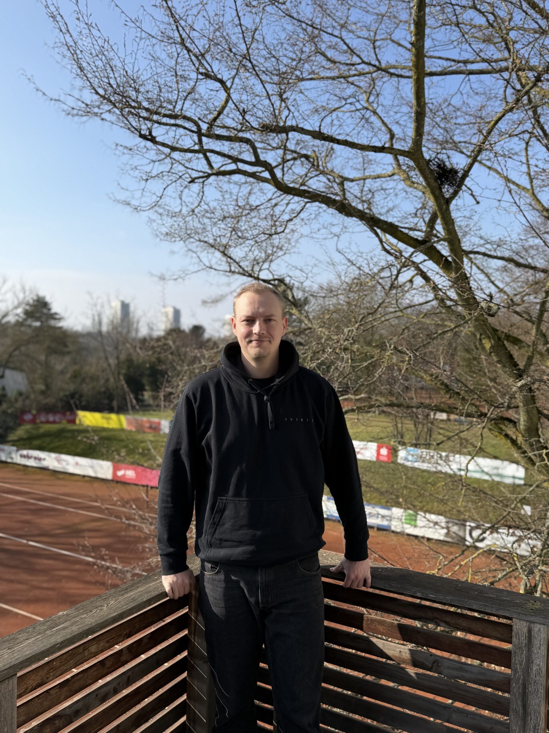 Mann auf Balkon über Tennisplatz im Park