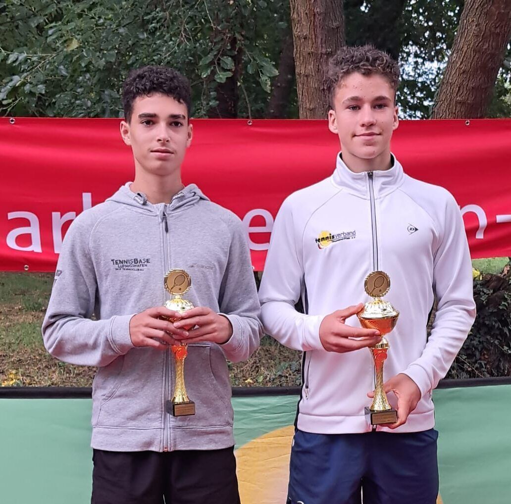Zwei junge Tennisspieler mit Pokalen im Freien
