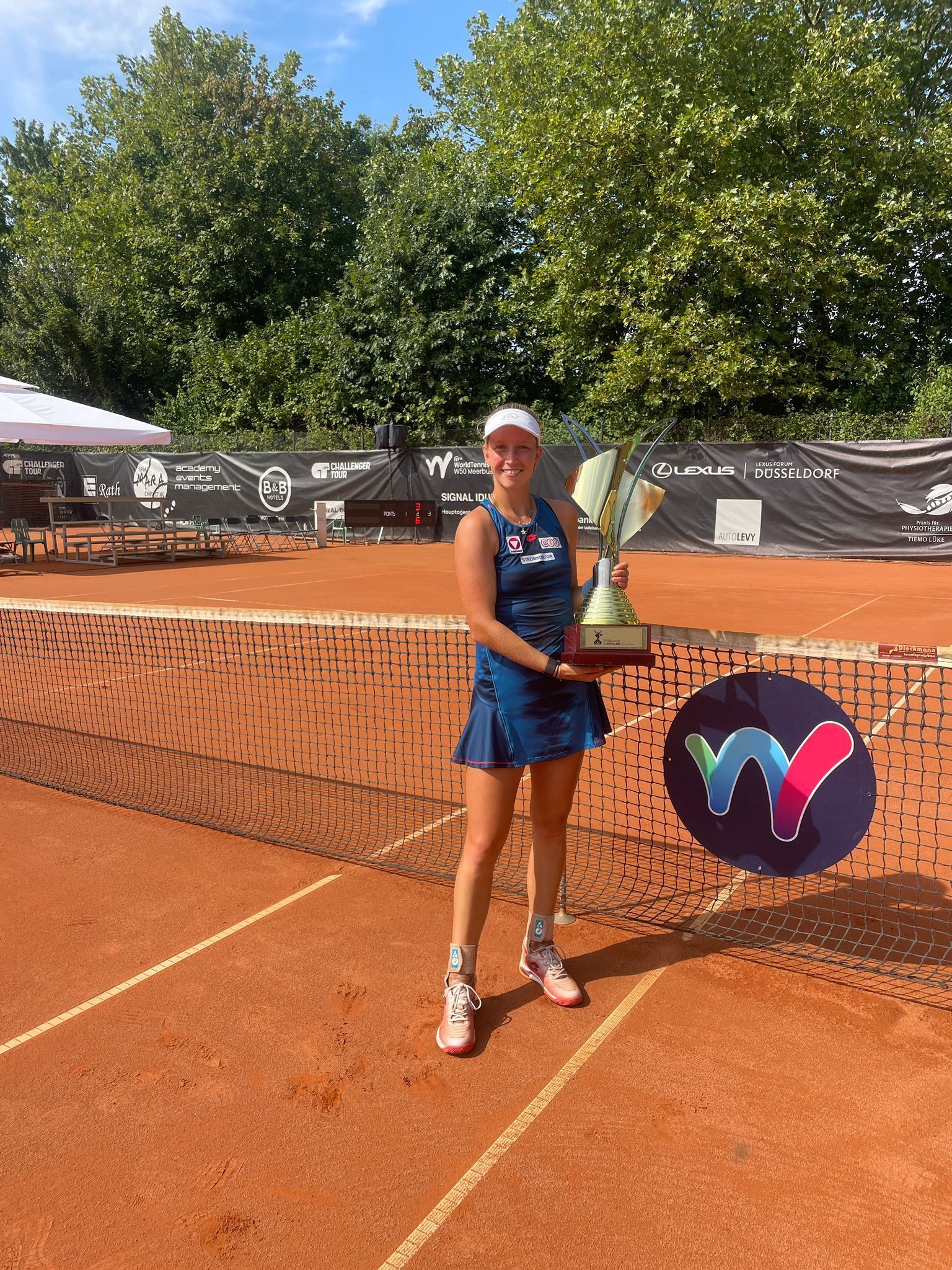 Tennisspielerin mit Pokal auf Sandplatz