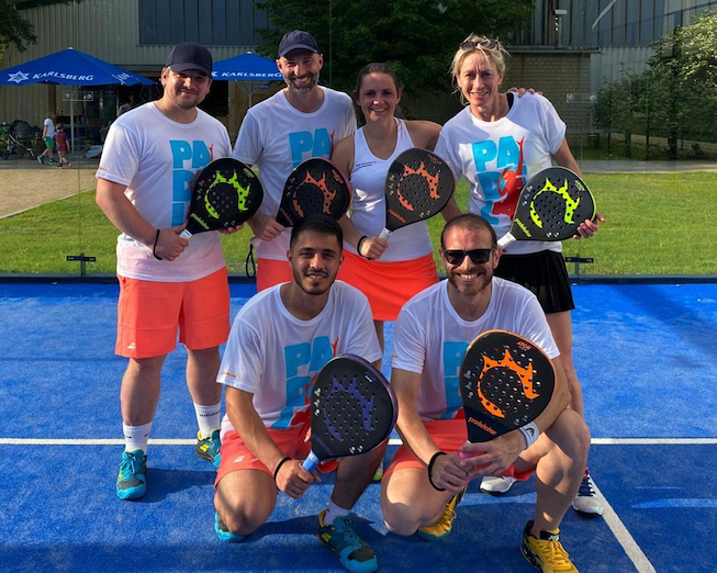 Sechs Padelspieler auf blauem Outdoor-Court