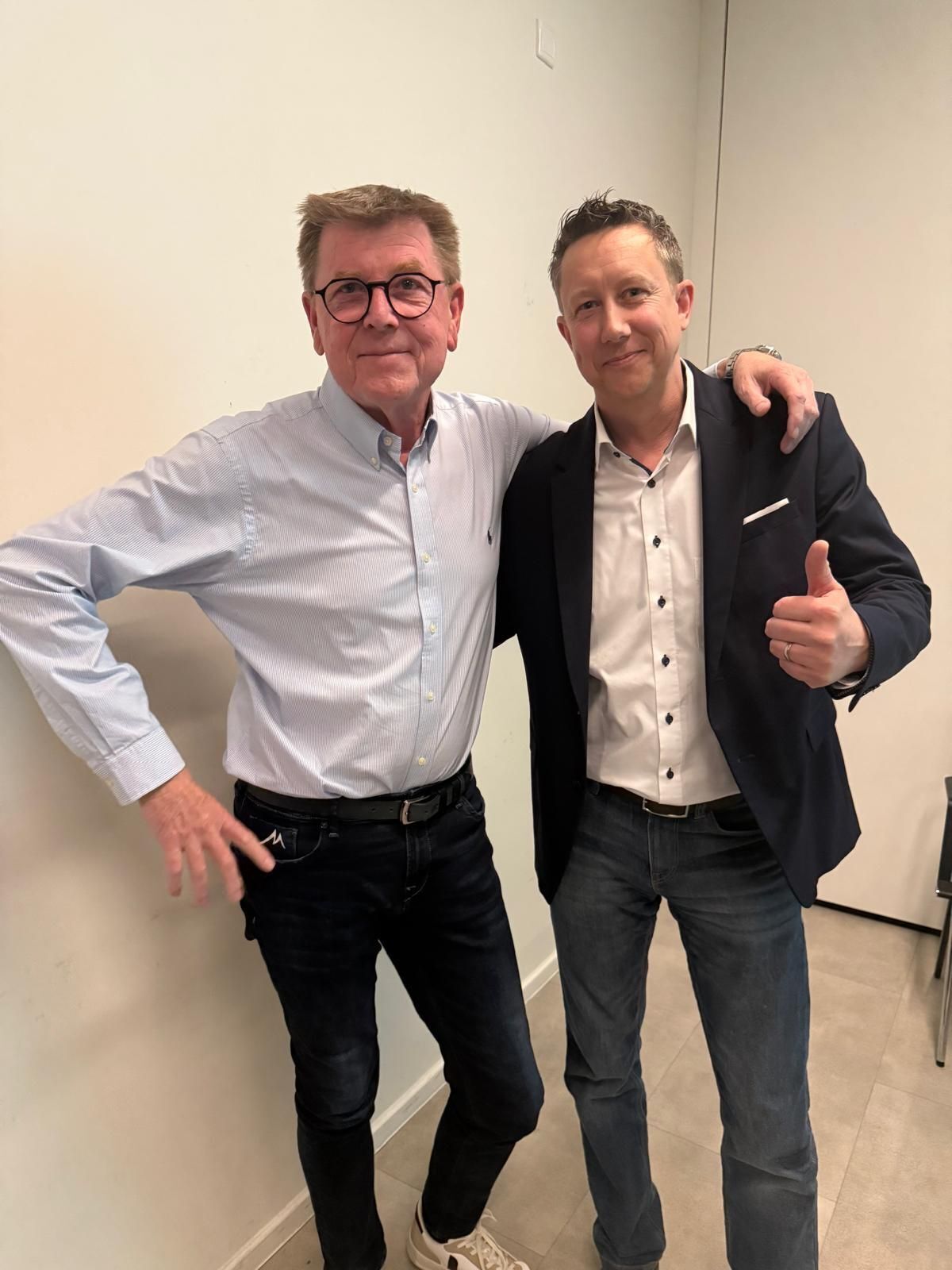 Zwei Männer posieren Arm in Arm drinnen