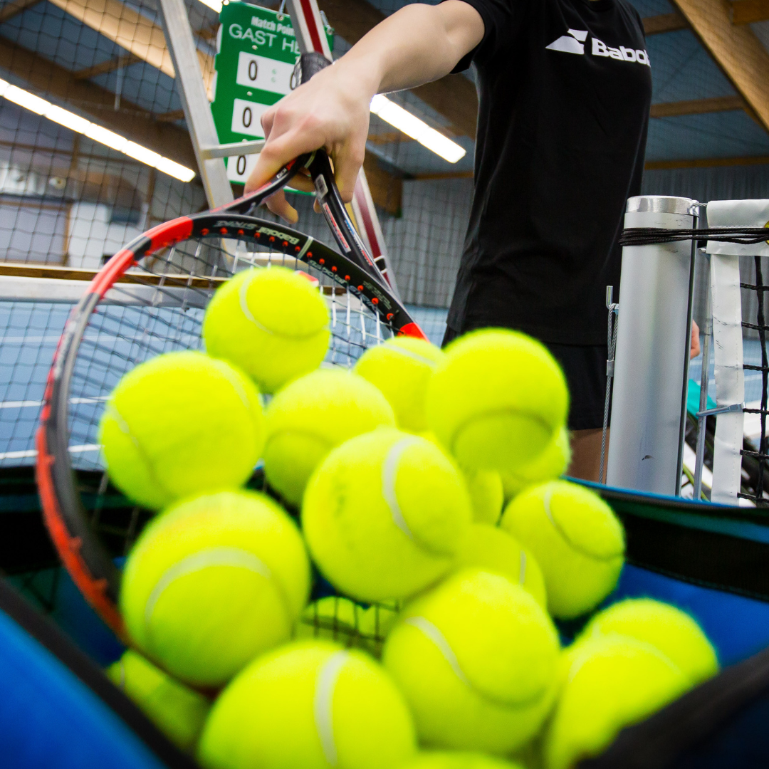 Tennisbälle im Korb auf Hallenplatz