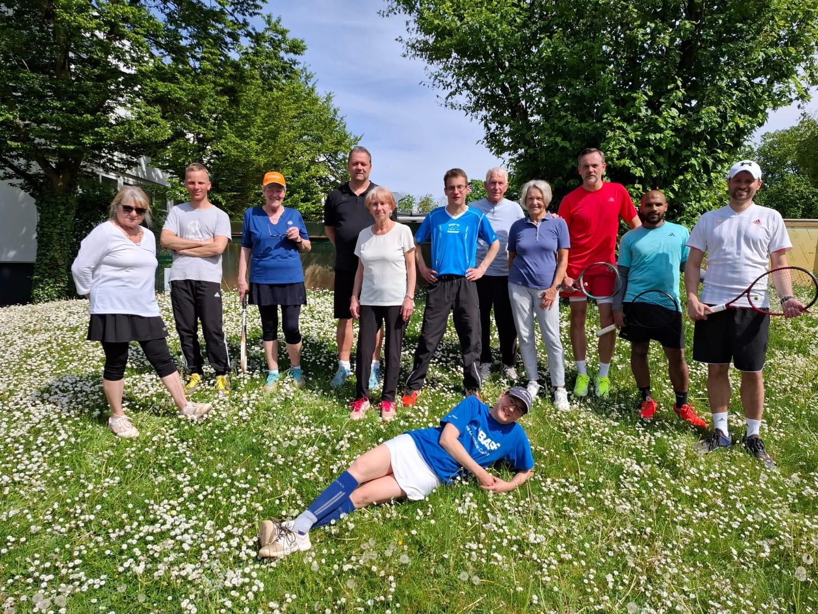 Tennisgruppe auf Blumenwiese im Sonnenschein