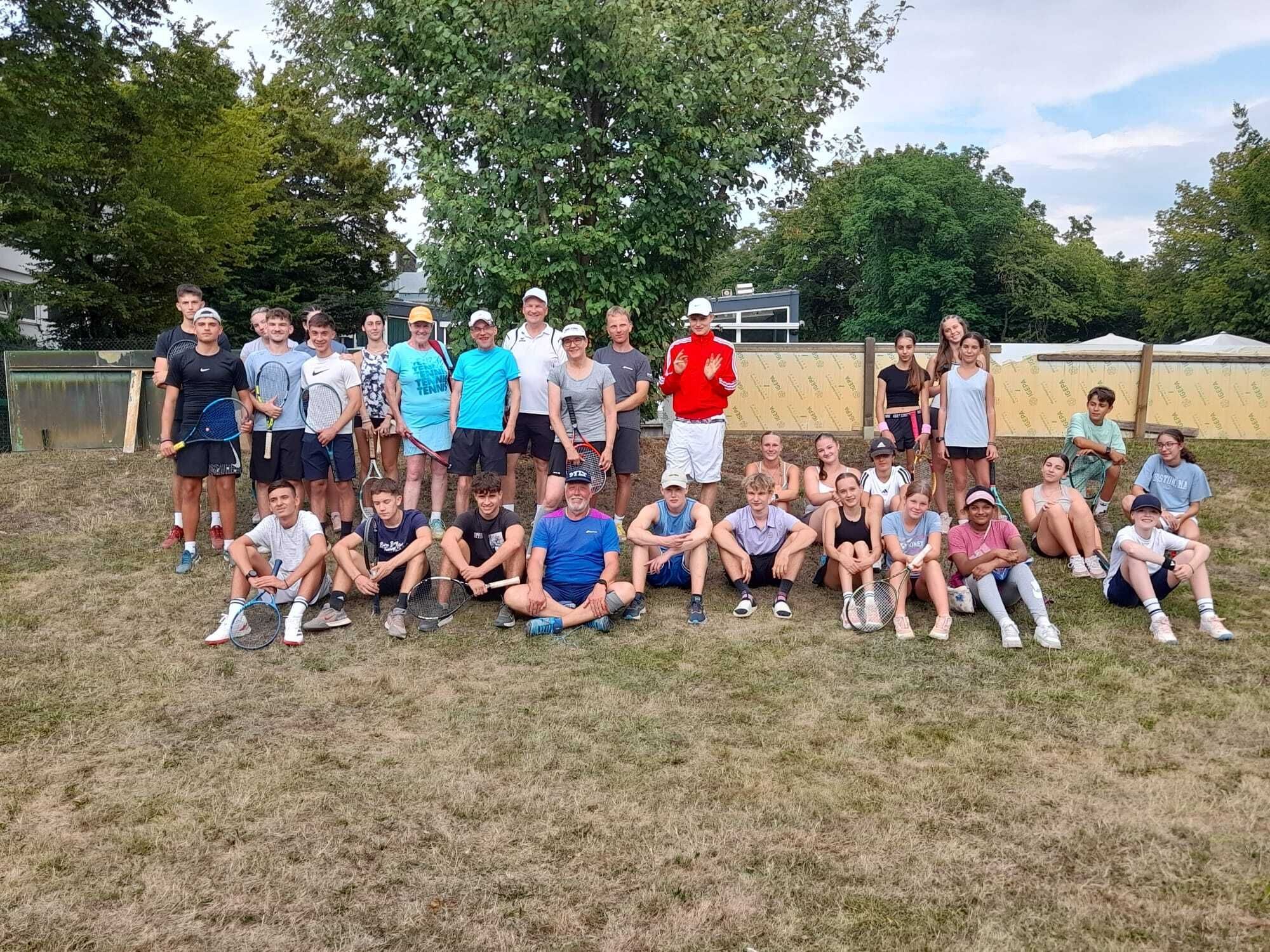 Große Tennisgruppe mit Schlägern auf Rasen