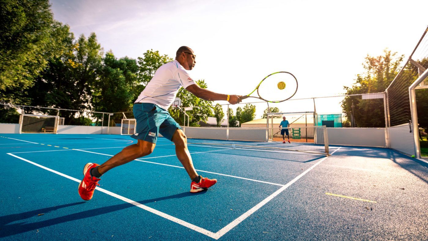 Mann spielt Tennis auf blauem Außenplatz