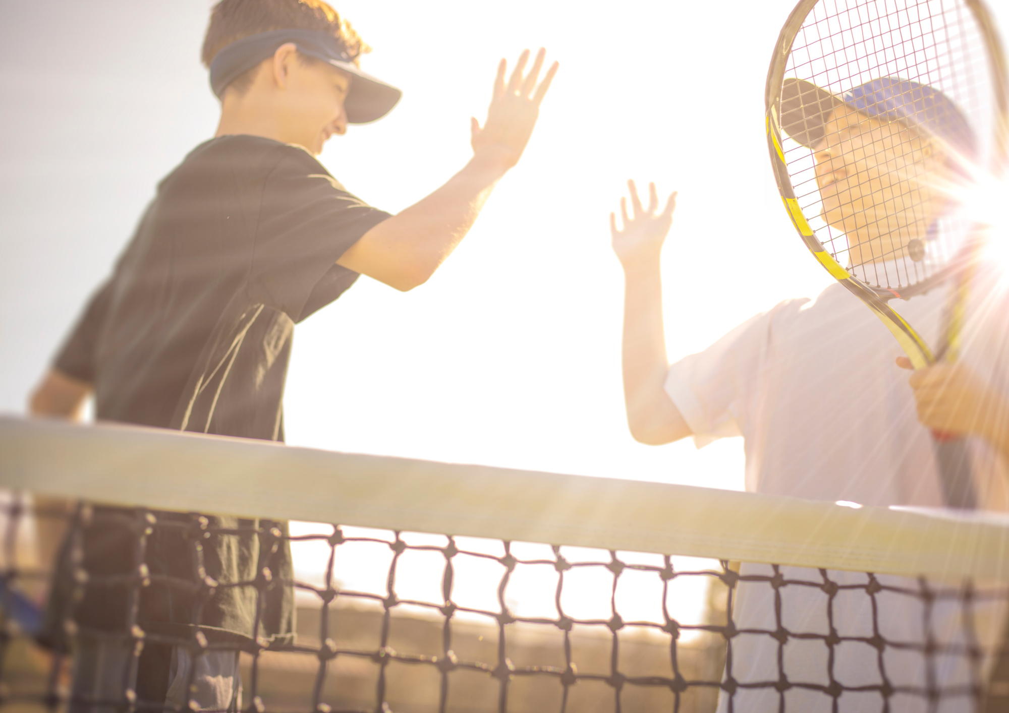 Zwei Jungen geben sich High-Five am Tennisnetz