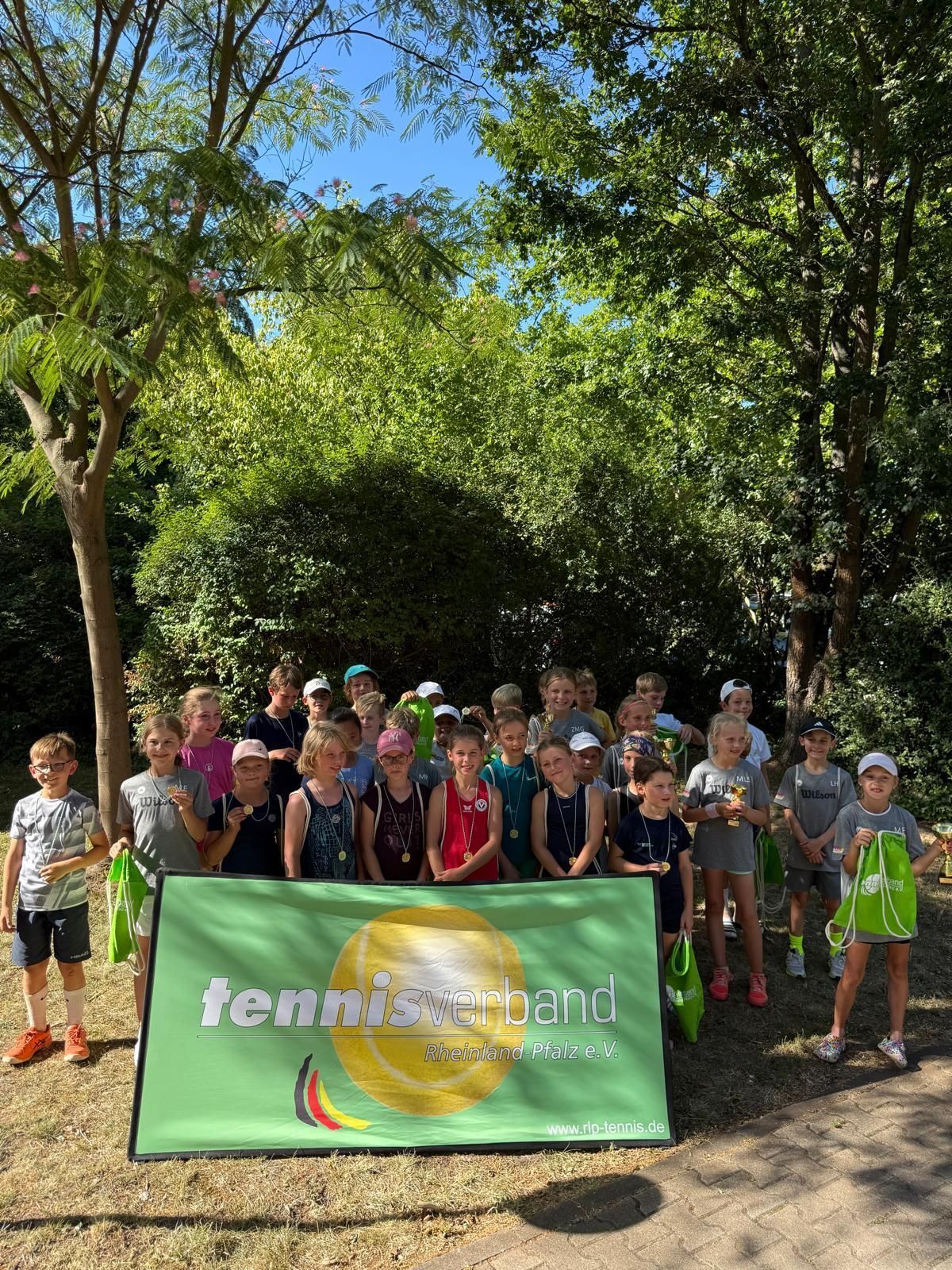 Kinder mit Medaillen beim Tennis-Event im Park