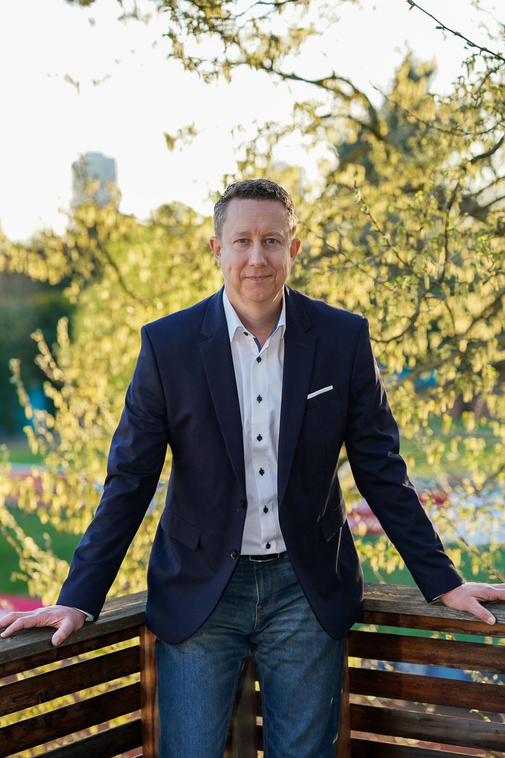 Mann im Sakko auf Balkon im Grünen