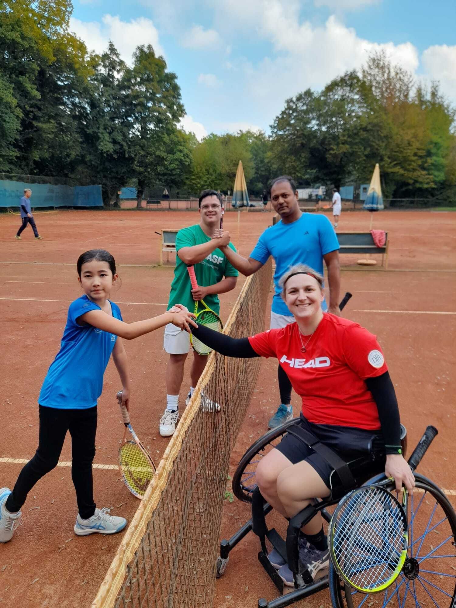 Tennisspieler begrüßen sich am Netz auf Sandplatz