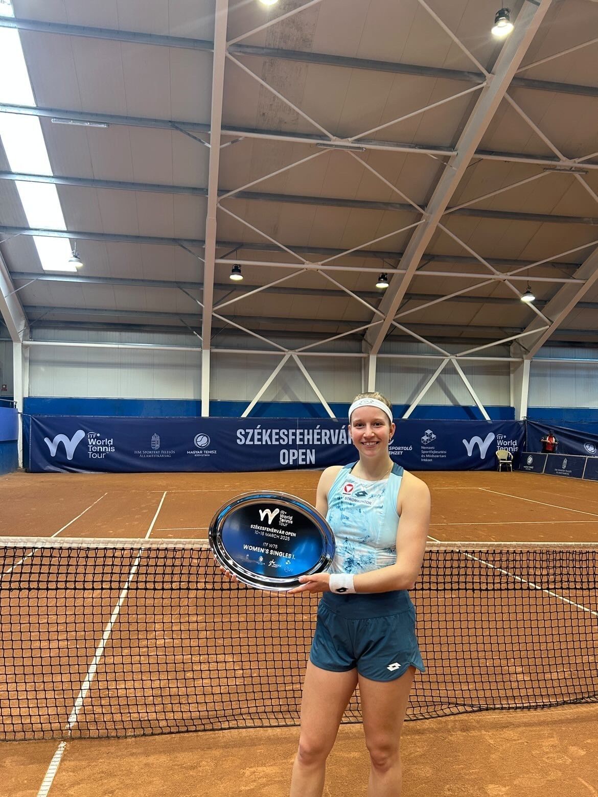 Tennisspielerin mit Trophäe auf Sandplatz