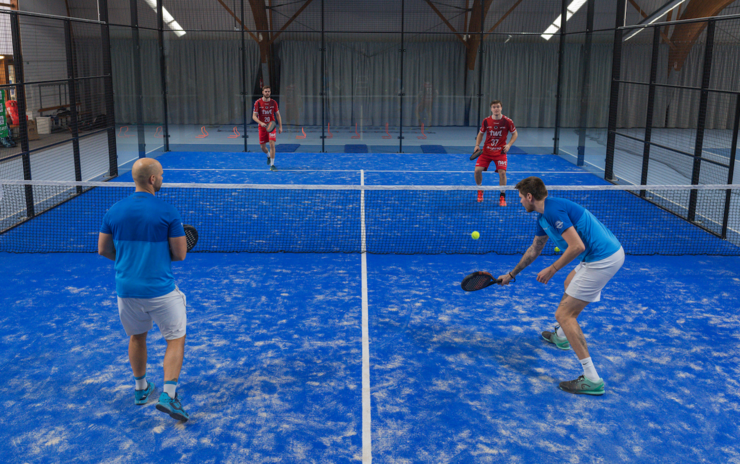 Vier Männer spielen Padel in Indoorhalle