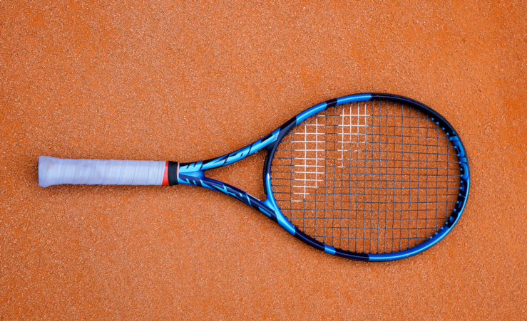 Tennisschläger auf rotem Sandplatz von oben