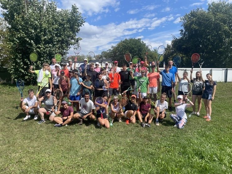 Große Gruppe mit Tennisschlägern auf Rasenplatz